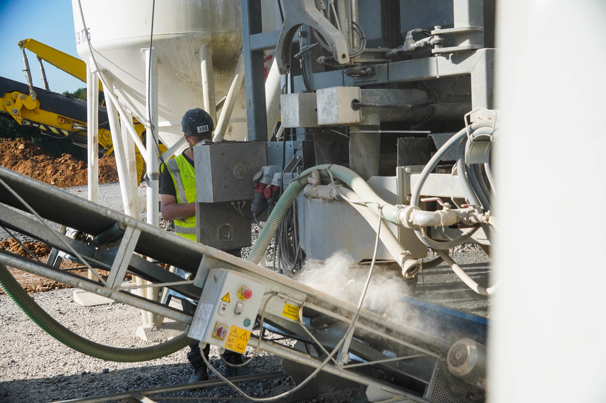 Mitarbeiter arbeiten an einer mobilen Flüssigbodenanlage auf einer Tiefbaustelle